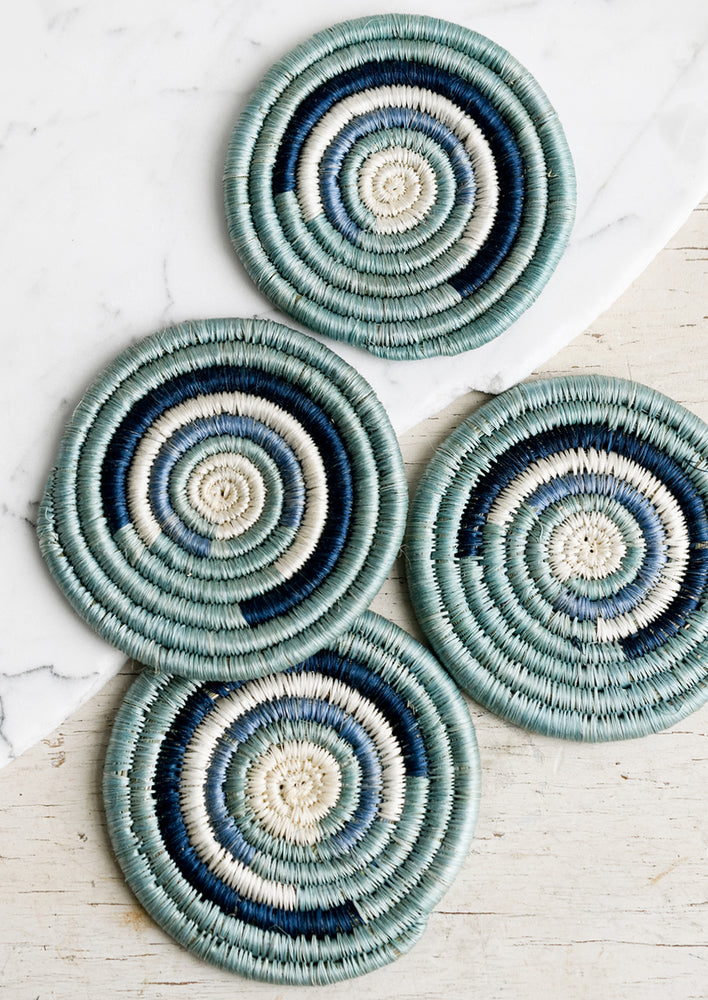 1: A set of four woven sweetgrass coasters in blue spiral design.