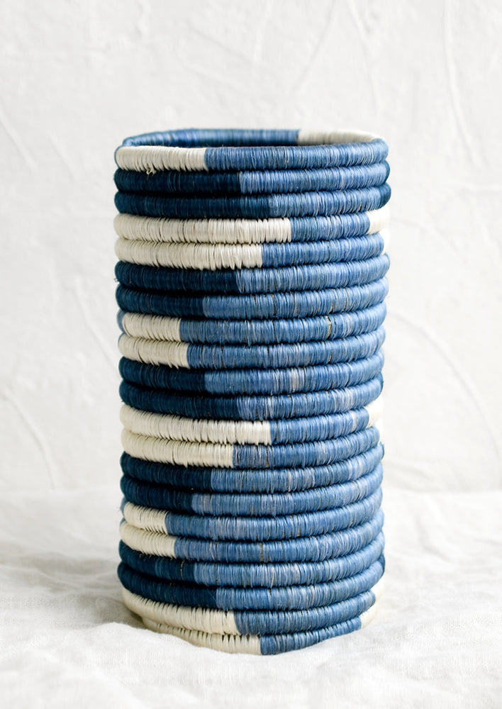 A woven sweetgrass vase in varying tones of blue, geometric design.