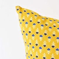 2: Detail shot of a block printed pillow with a yellow, blue, and white floral design.