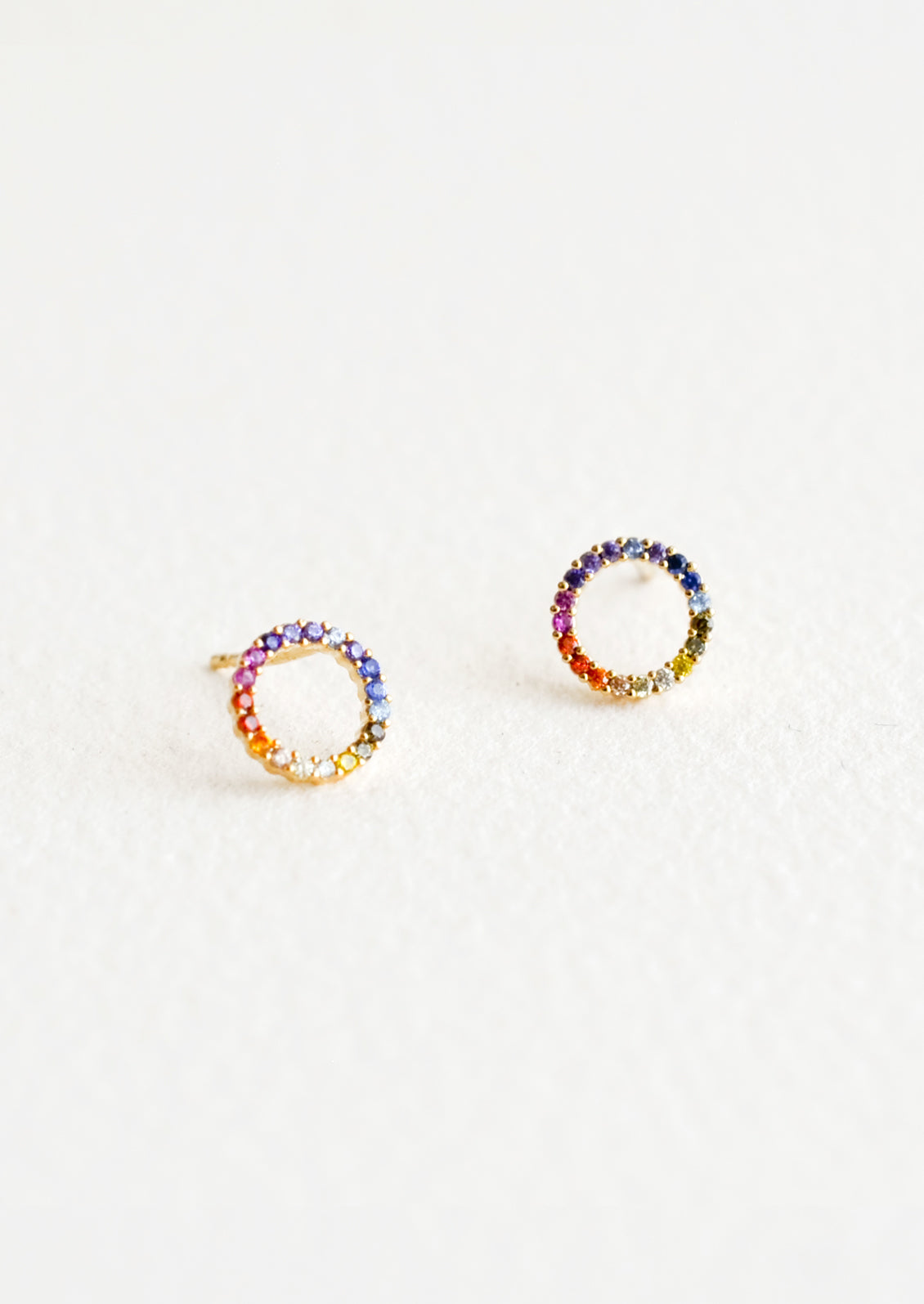 Stud earrings in open circle shape with colored rainbow crystals around.