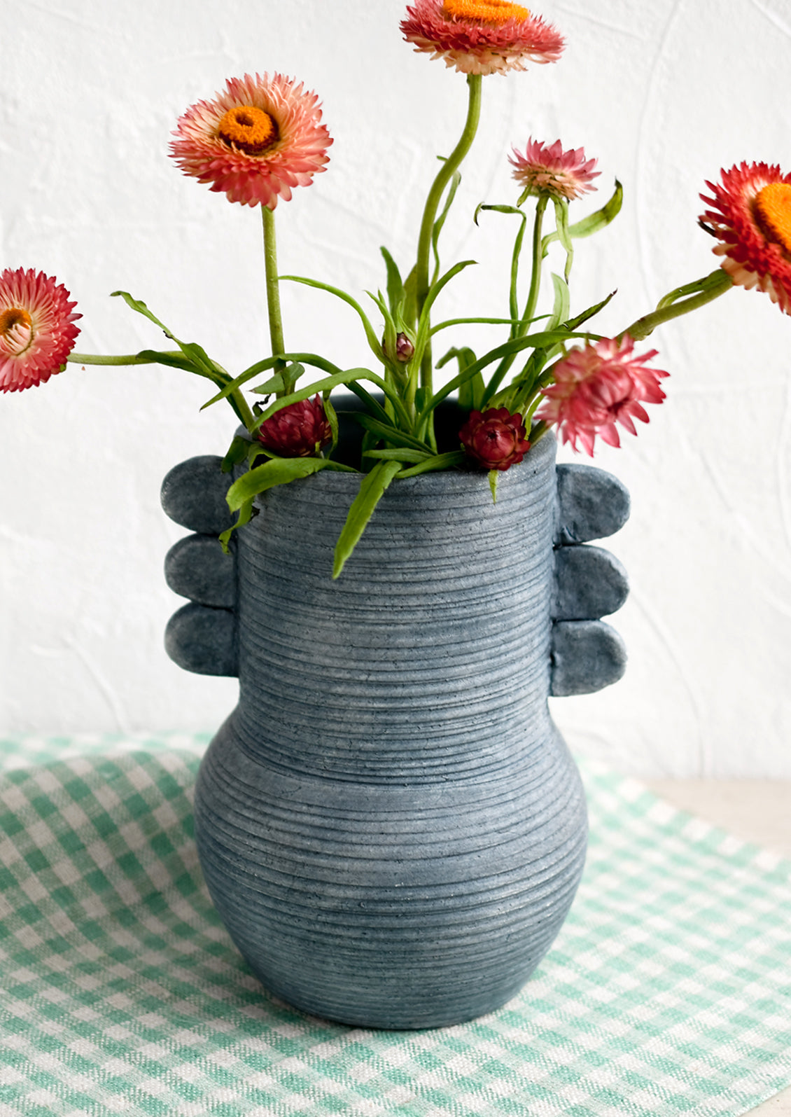 An ocean blue ceramic vase with etched ribbing and side tabs.