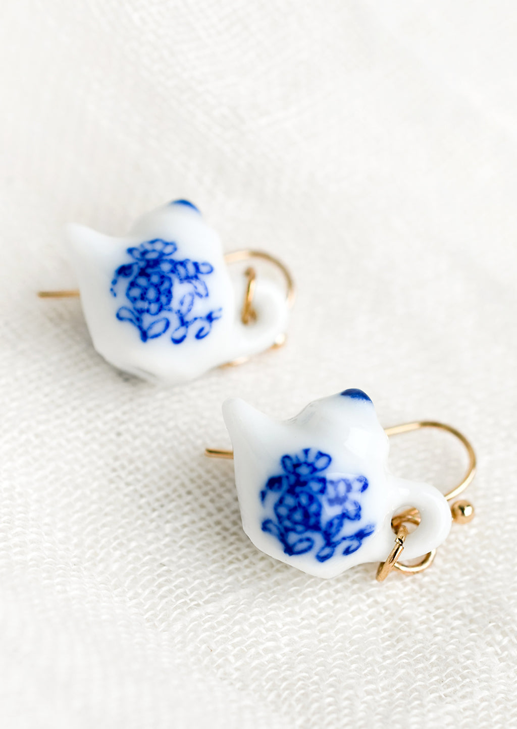 1: A pair of earrings in shape of white teapot with blue floral print.
