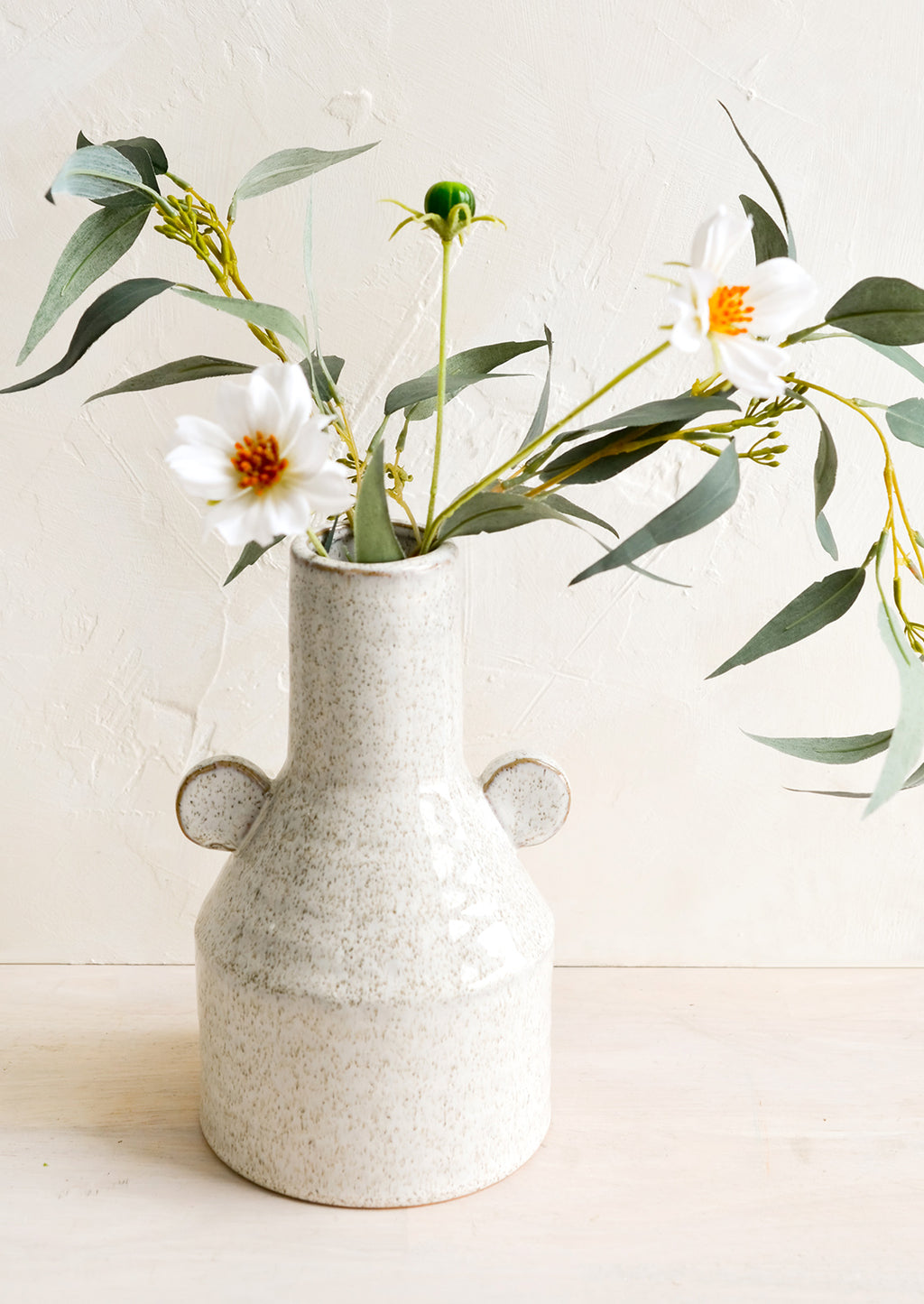 2: A speckled ceramic vase with flowers.
