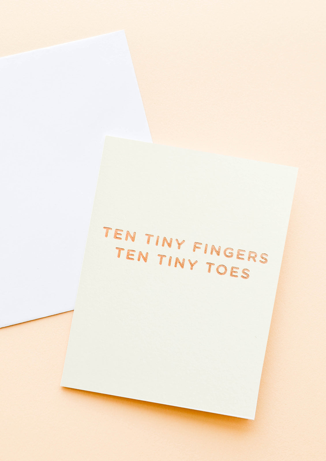 A pale yellow greeting card with gold foil text reading "ten tiny fingers ten tiny toes."
