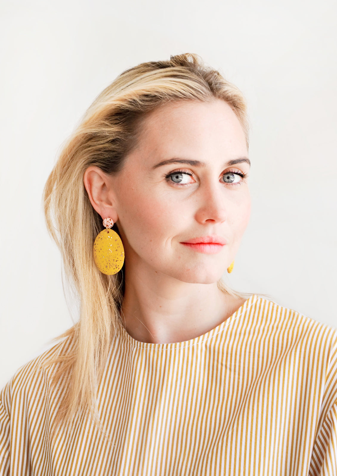 Model shot showing woman wearing earrings and a peach top.