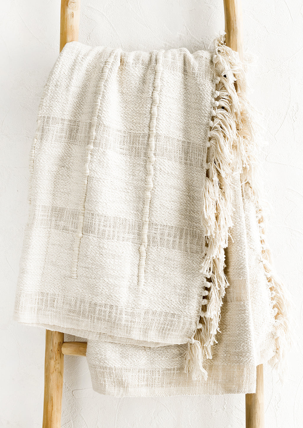 1: A natural cotton throw with paneling detailing and fringed trim.
