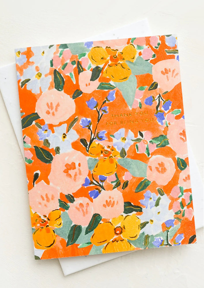 A greeting card in orange floral print with small lettering reading "Thank You For Being You".