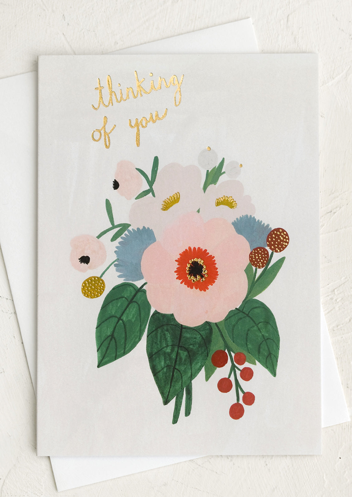 A floral print card with gold text reading "Thinking of you".