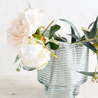 2: A ribbed blue glass vase with peonies.