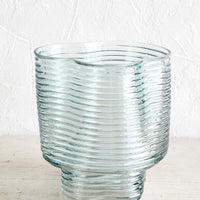 1: A curvy flower vase in light blue ribbed glass.