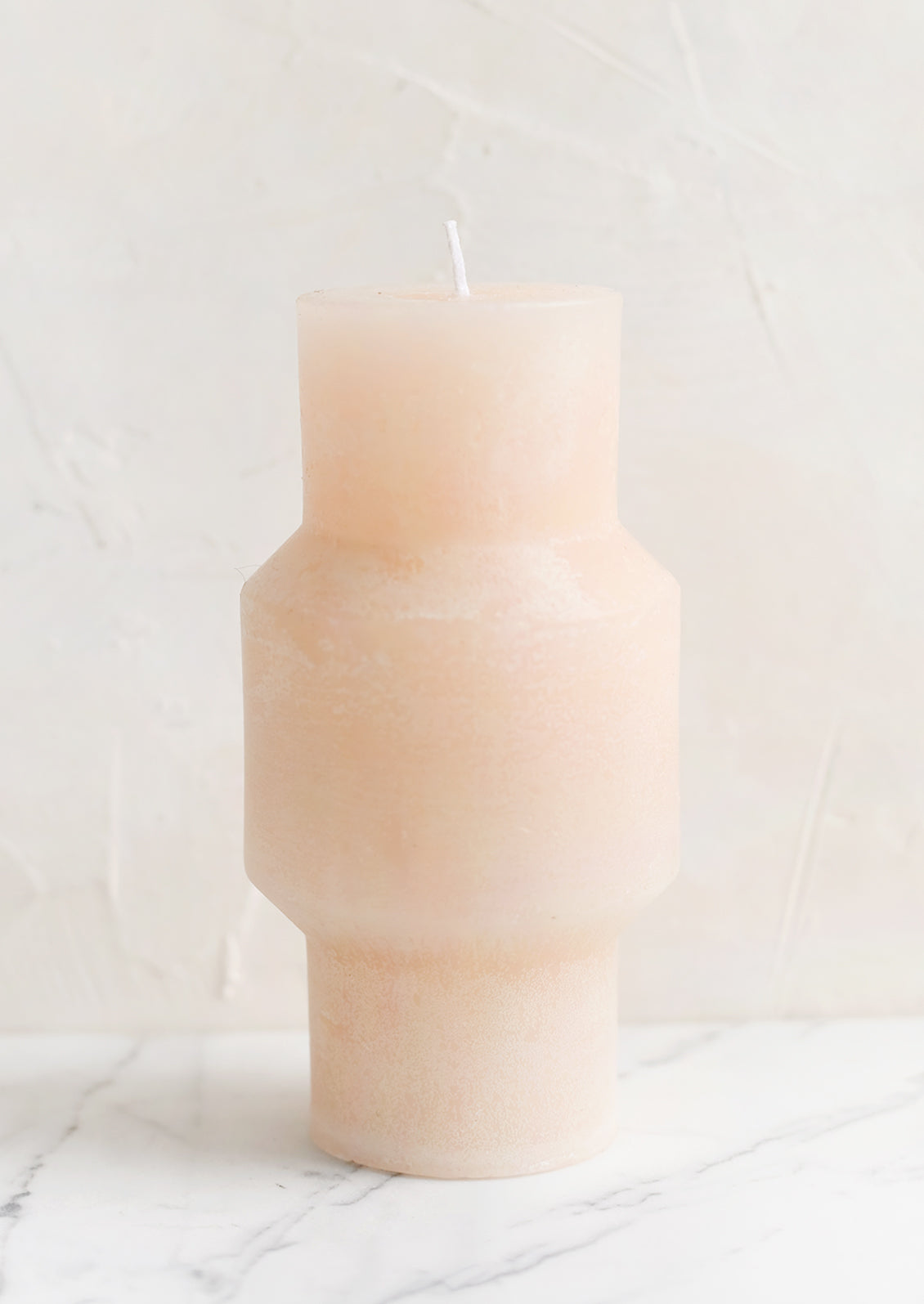 A medium carved pillar candle with waxy finish in petal.