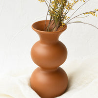 2: An hourglass shaped vase in terracotta filled with yellow flowers