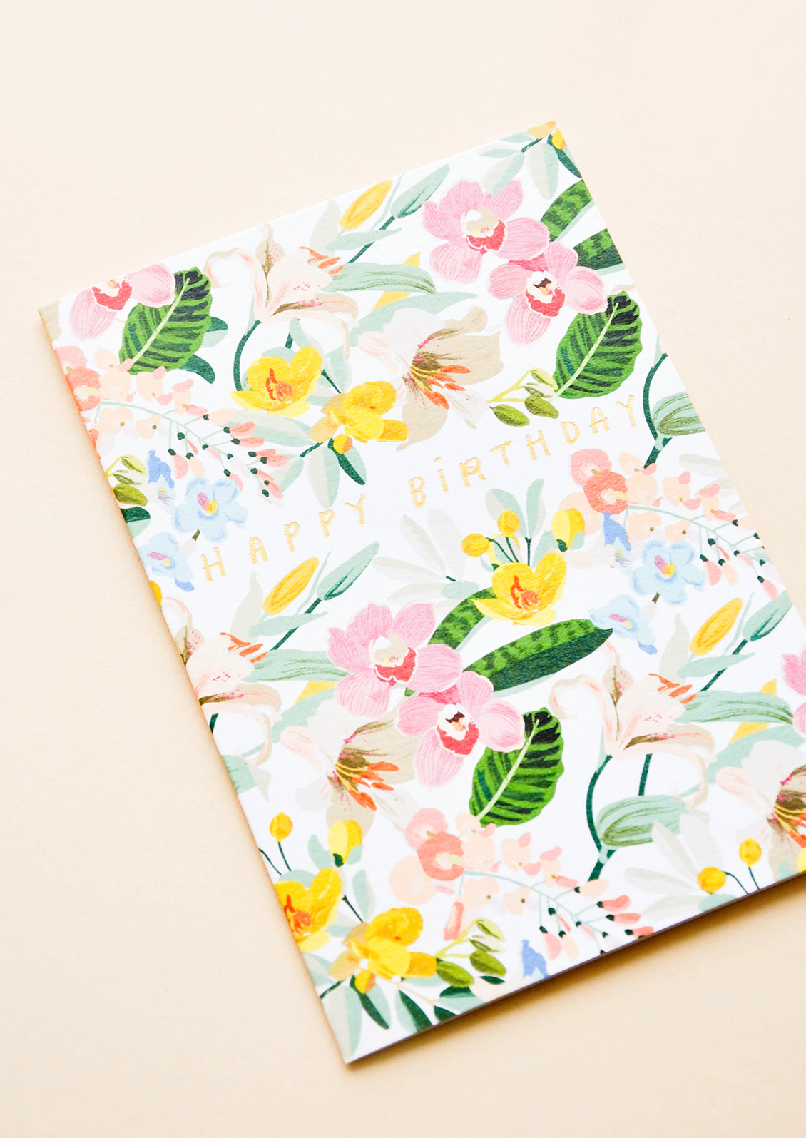 Greeting card with bright white floral background and gold lettering reading "Happy Birthday"