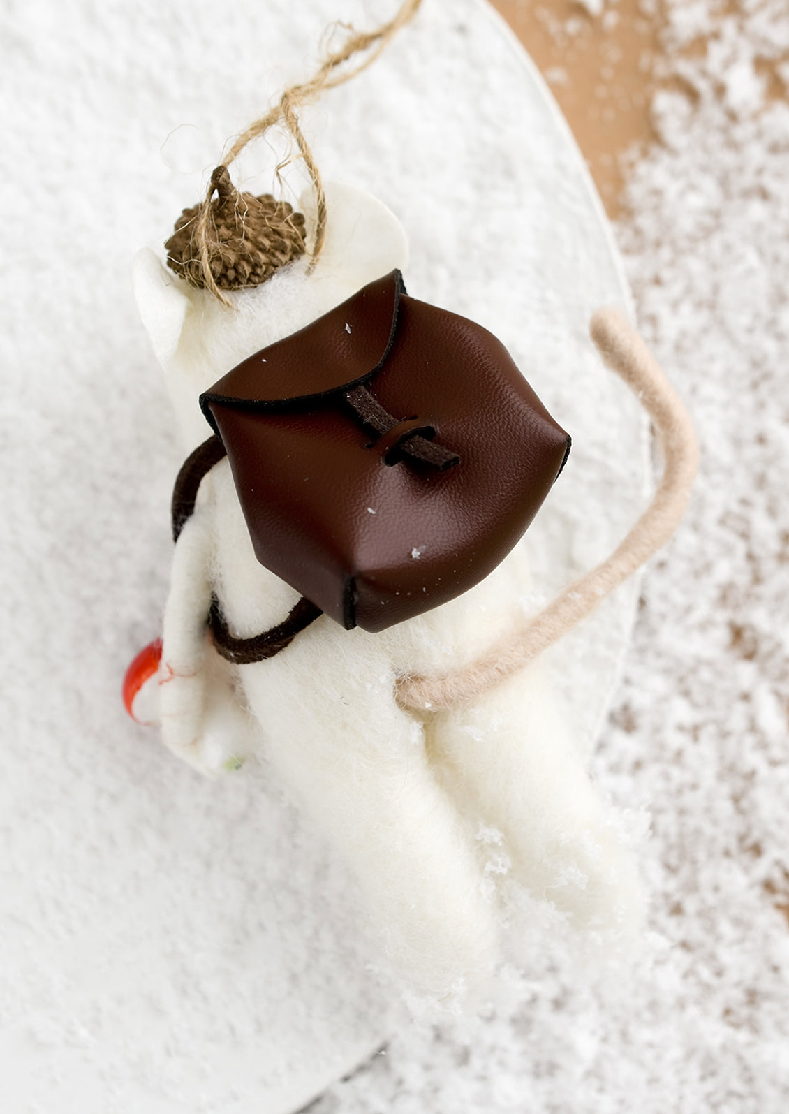 A felted holiday ornament of a mouse with a leather satchel.