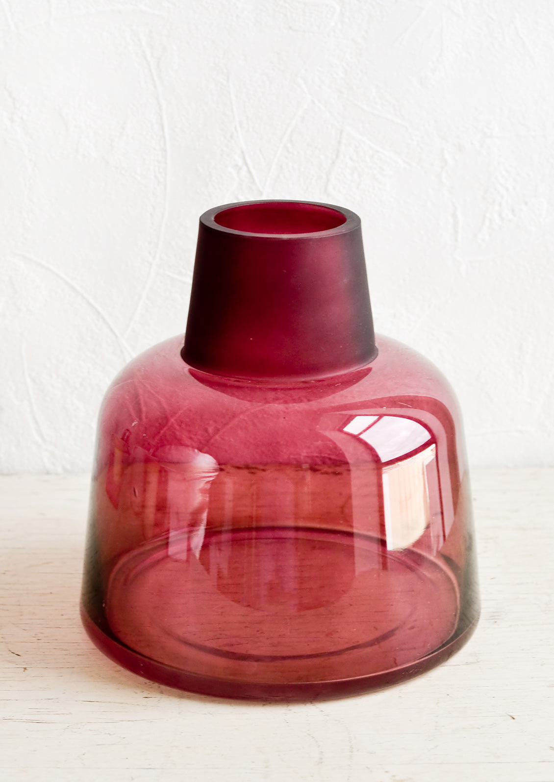A glass vase in polished berry-colored glass with tapered, frosted opening in same color.