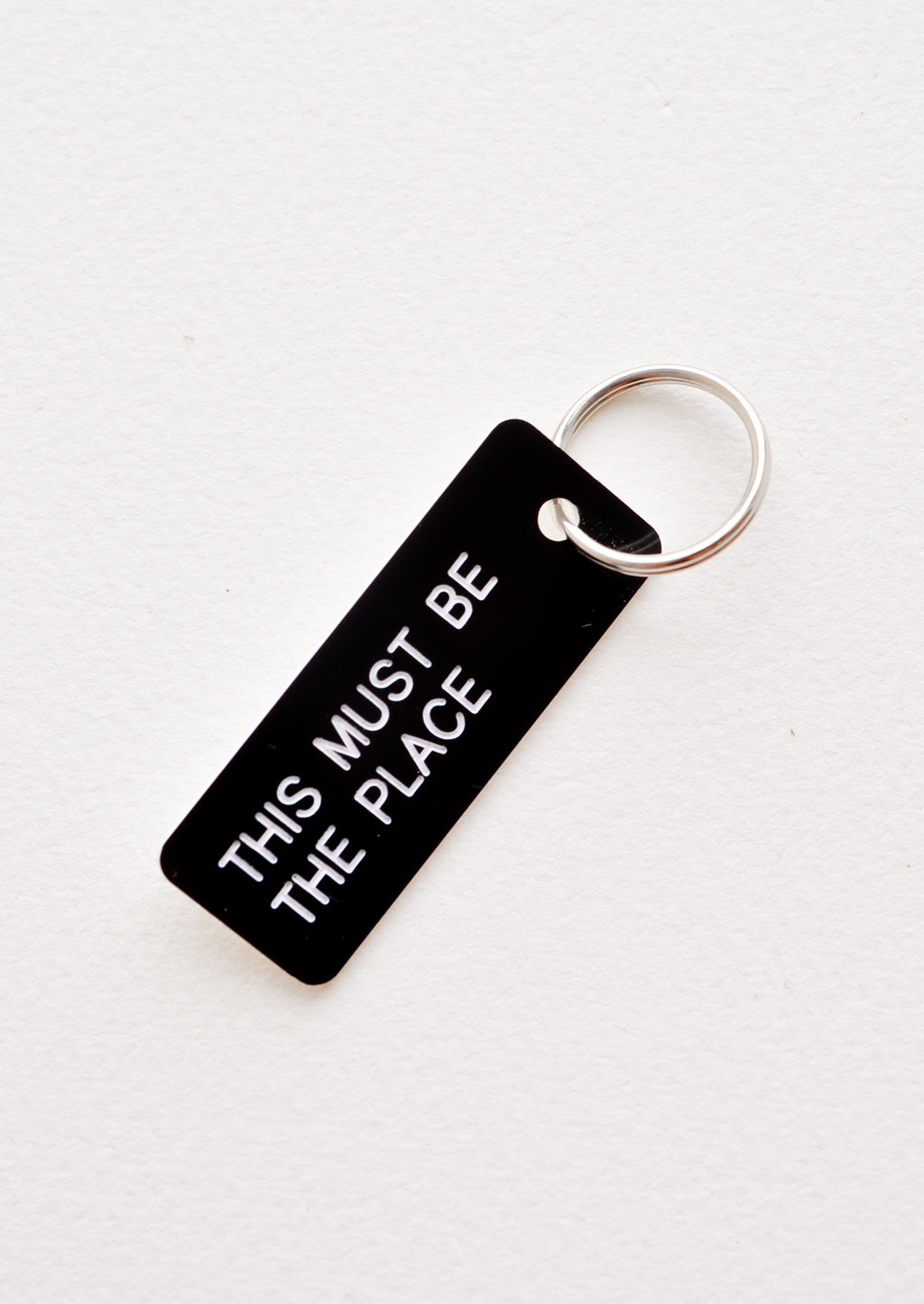 This Must Be The Place: Small acrylic keychain, black background with white words that says "THIS MUST BE THE PLACE"