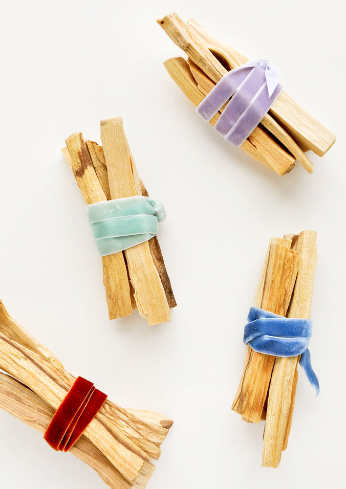 Four bundles of wooden sticks wrapped in red, green, purple, or blue velvet ribbon.