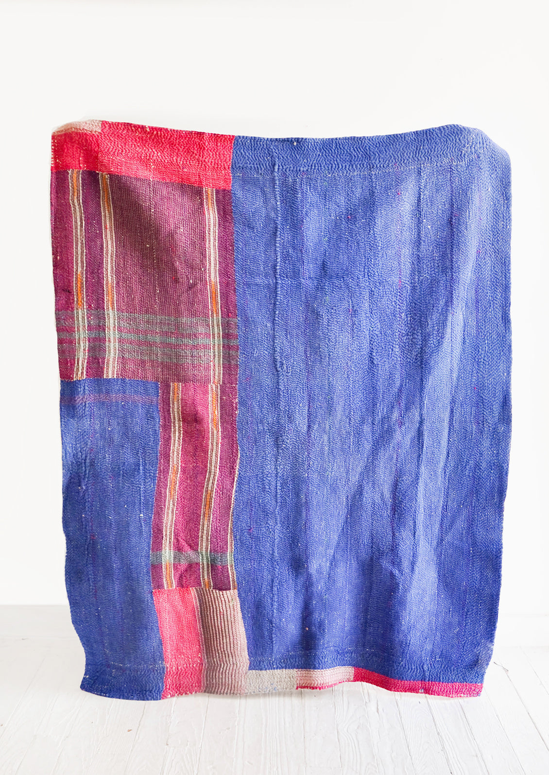 Vintage patchwork quilt in a mix of colors and fabrics. Predominantly dark blue with magenta accents.