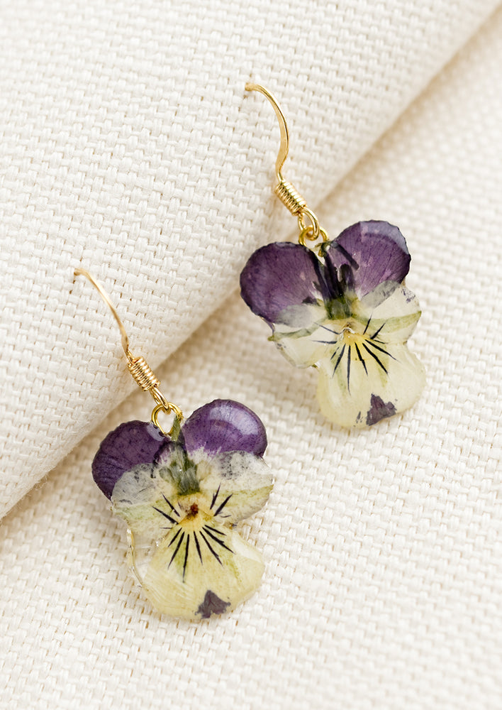 A pair of earrings made from dried viola flowers.