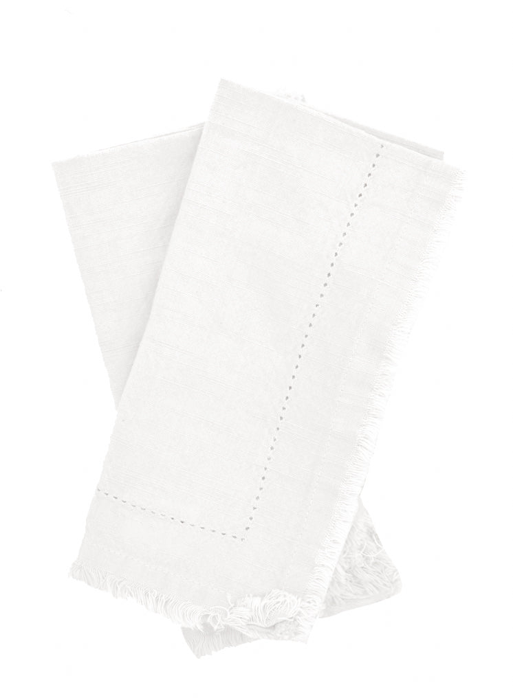 Two folded ivory Cotton Napkins with frayed edges .