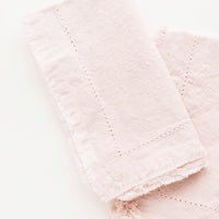 Dusty Rose: Two folded pink Cotton Napkins with frayed edges .