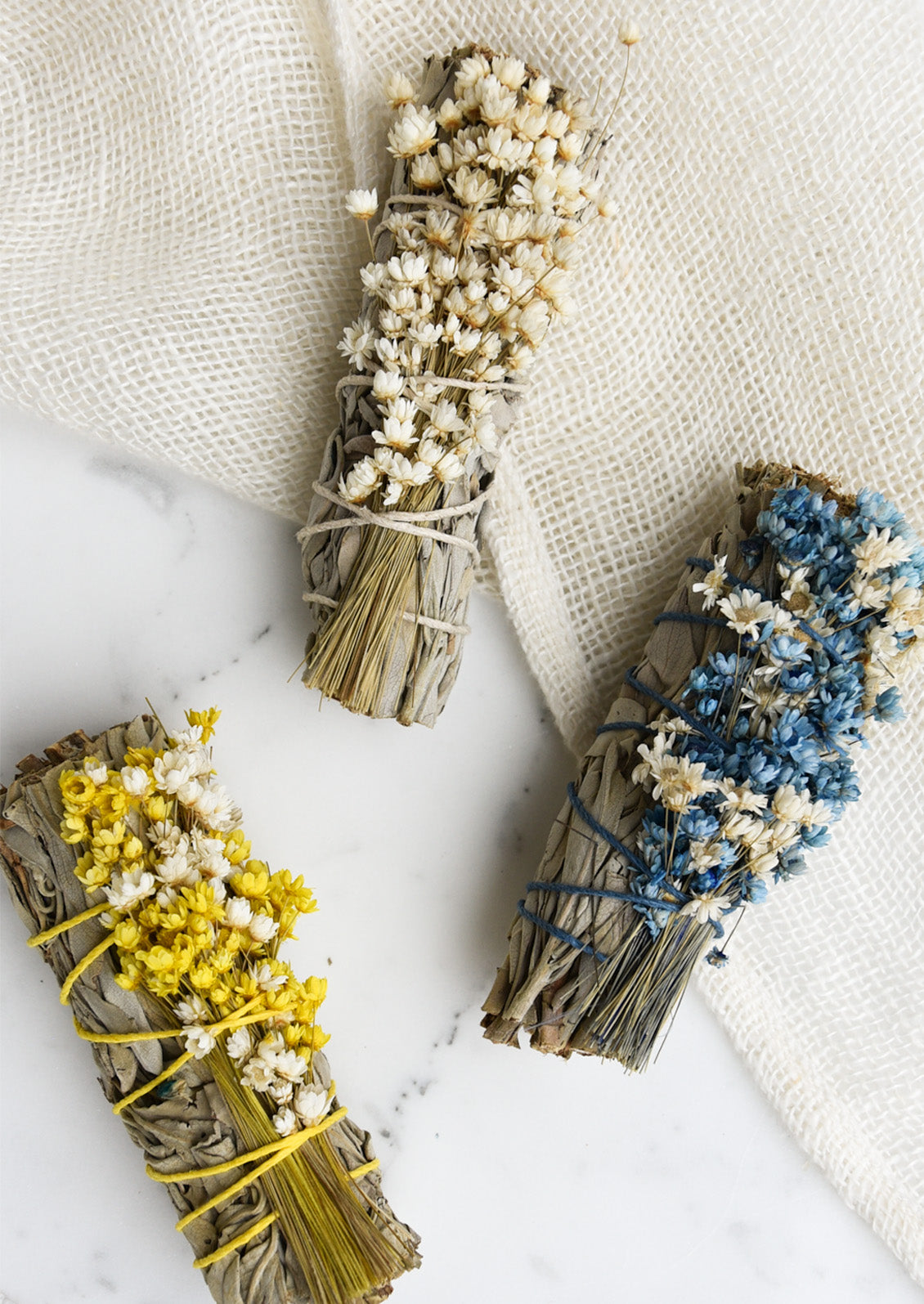 Three sage smudge bundles with wildflowers