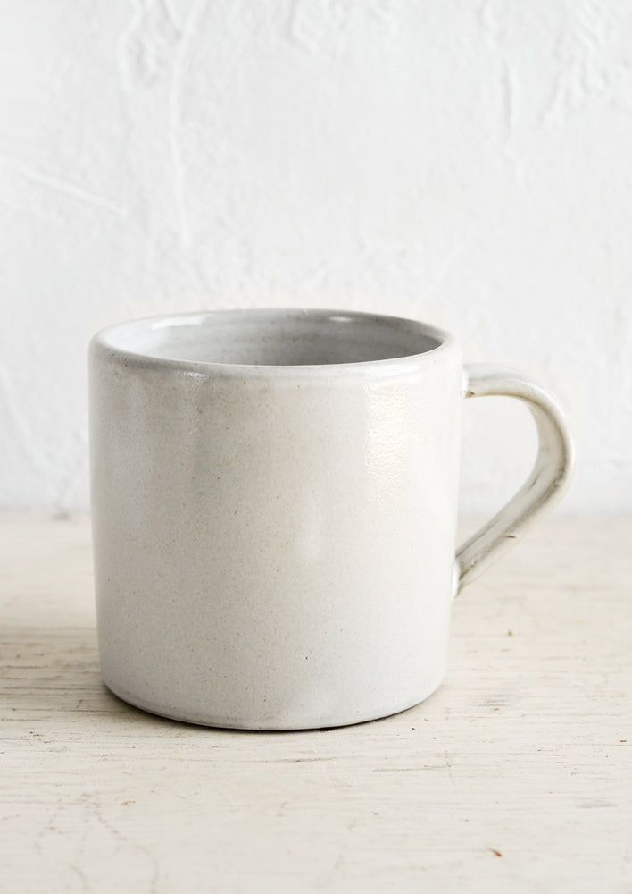 A ceramic coffee mug in a simple, classic shape in a white glaze over brown clay.