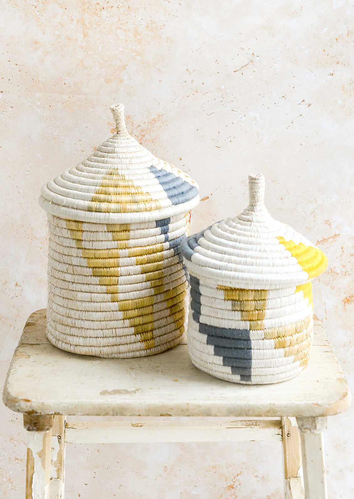 Woven lidded storage baskets with geometric patterns in small and medium sizes.