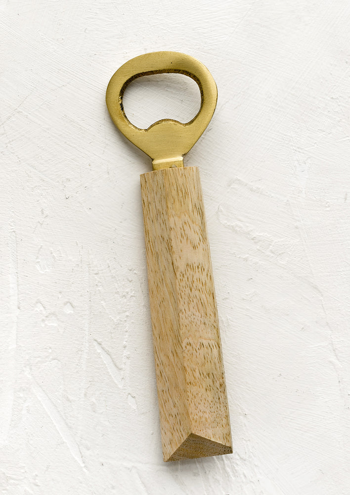 A brass bottle opener with faceted wood handle.