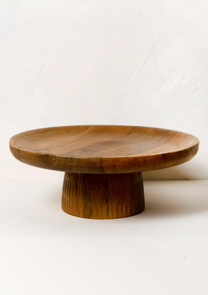 1: A wooden cake stand in mango wood with line textured base.