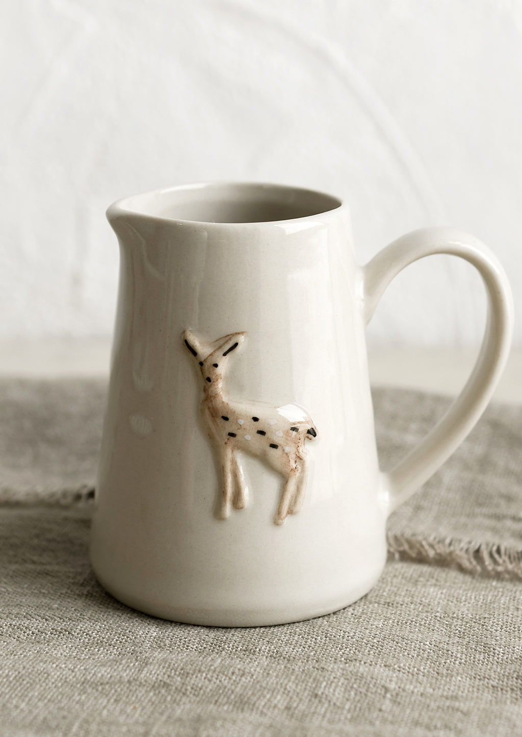 Deer: A small creamer pitcher in natural ivory with deer motif.