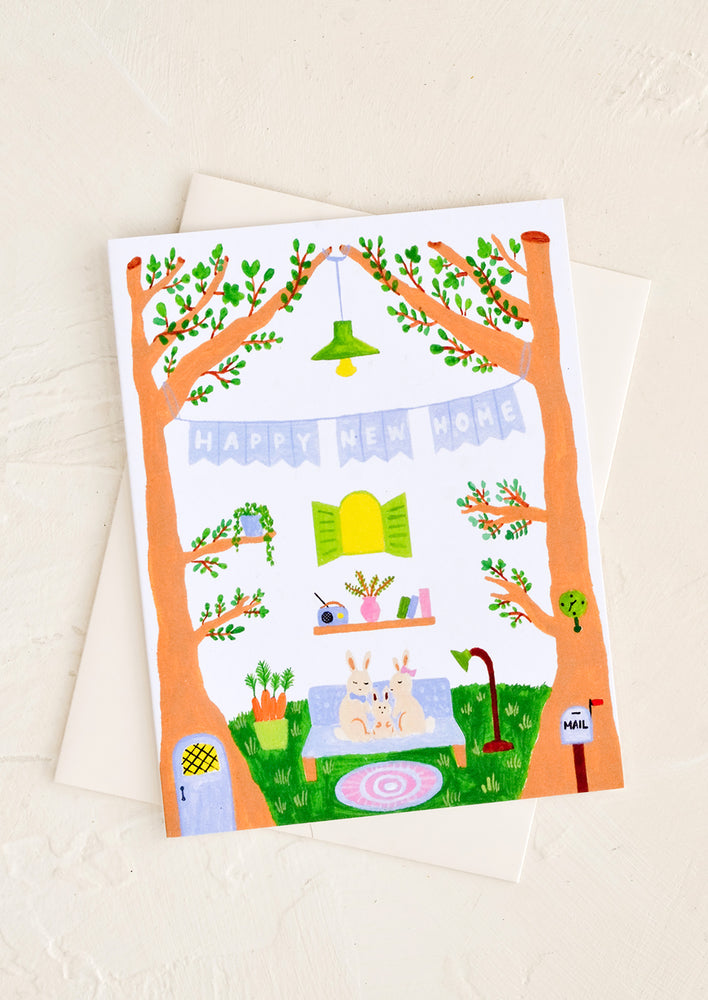 A greeting card with whimsical illustration of family in rabbits in treehouse.