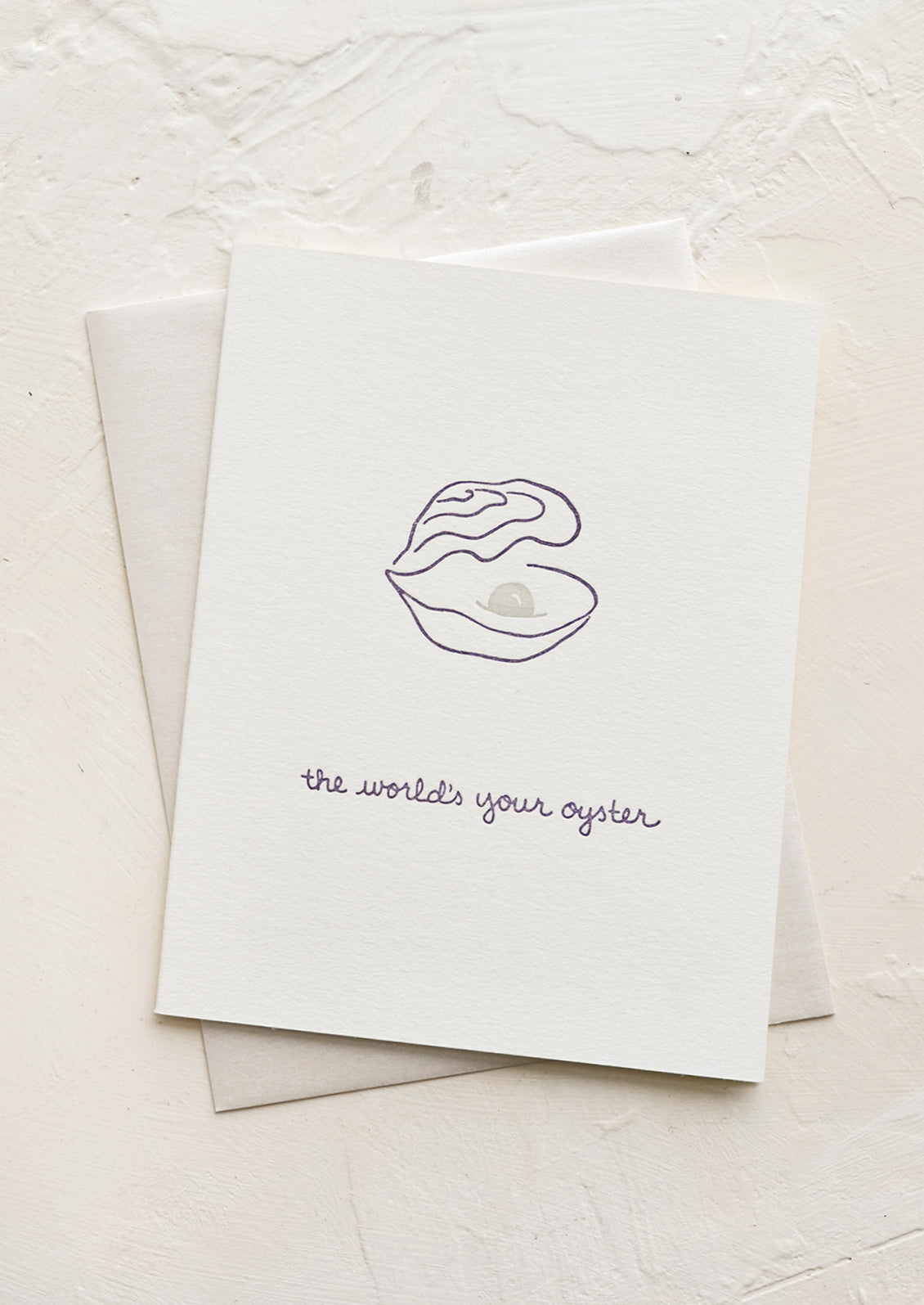 A greeting card with oyster and pearl with text below reading "The world's your oyster".