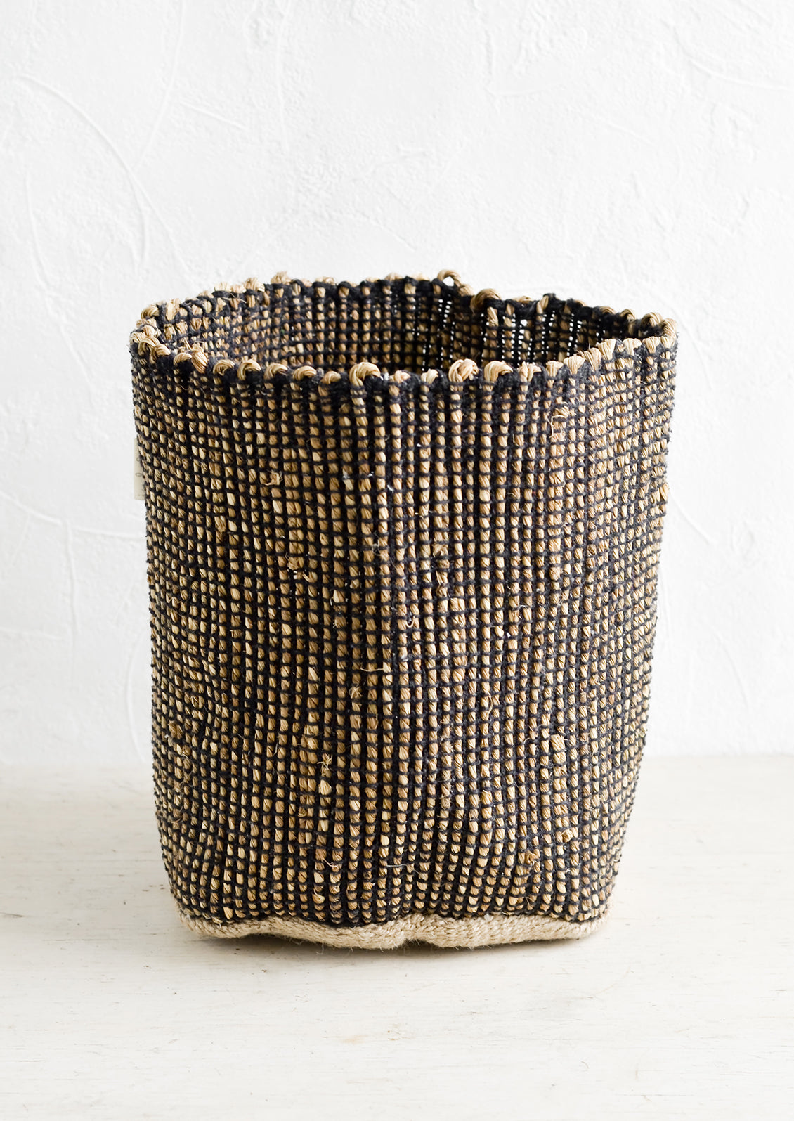 A soft sided storage bin made from black & natural seagrass.