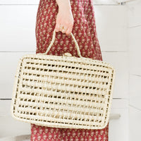 Large: A women holding a woven suitcase.