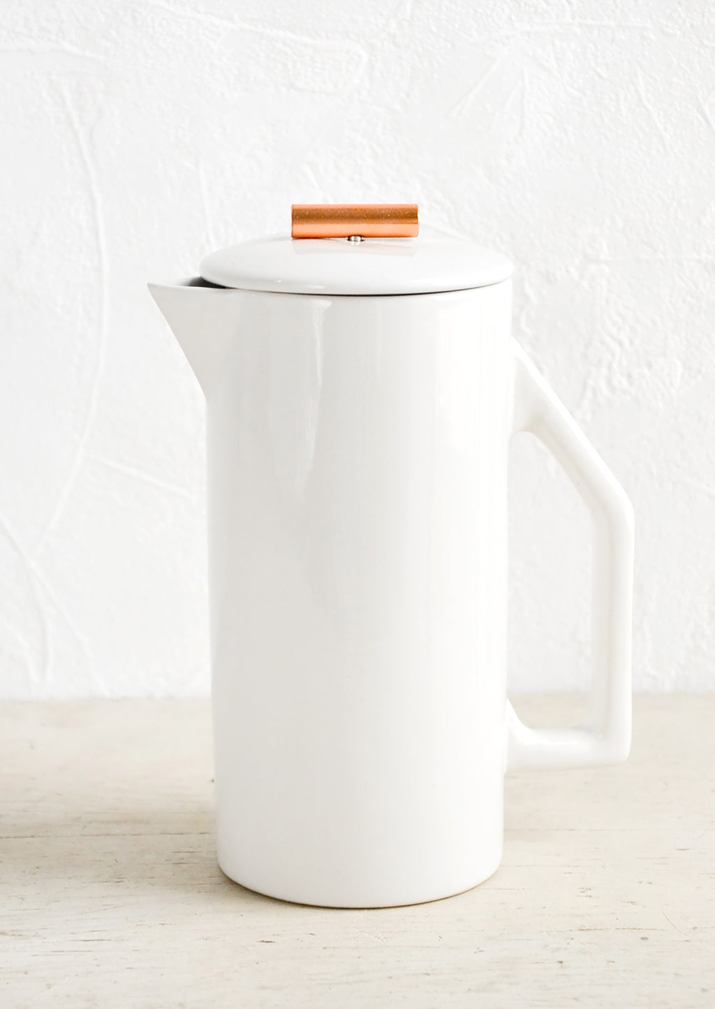 White Ceramic: A french press coffee maker made from white ceramic with a copper rod on lid.