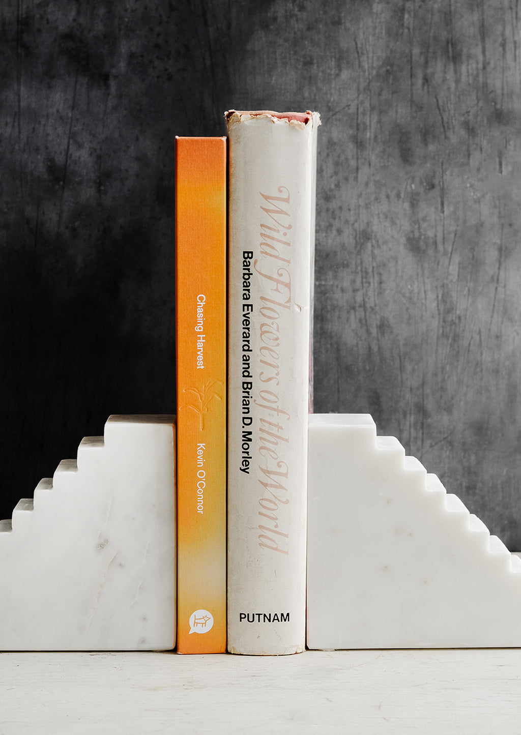 2: A pair of white marble bookends with staircase design, shown with two books.