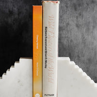 2: A pair of white marble bookends with staircase design, shown with two books.