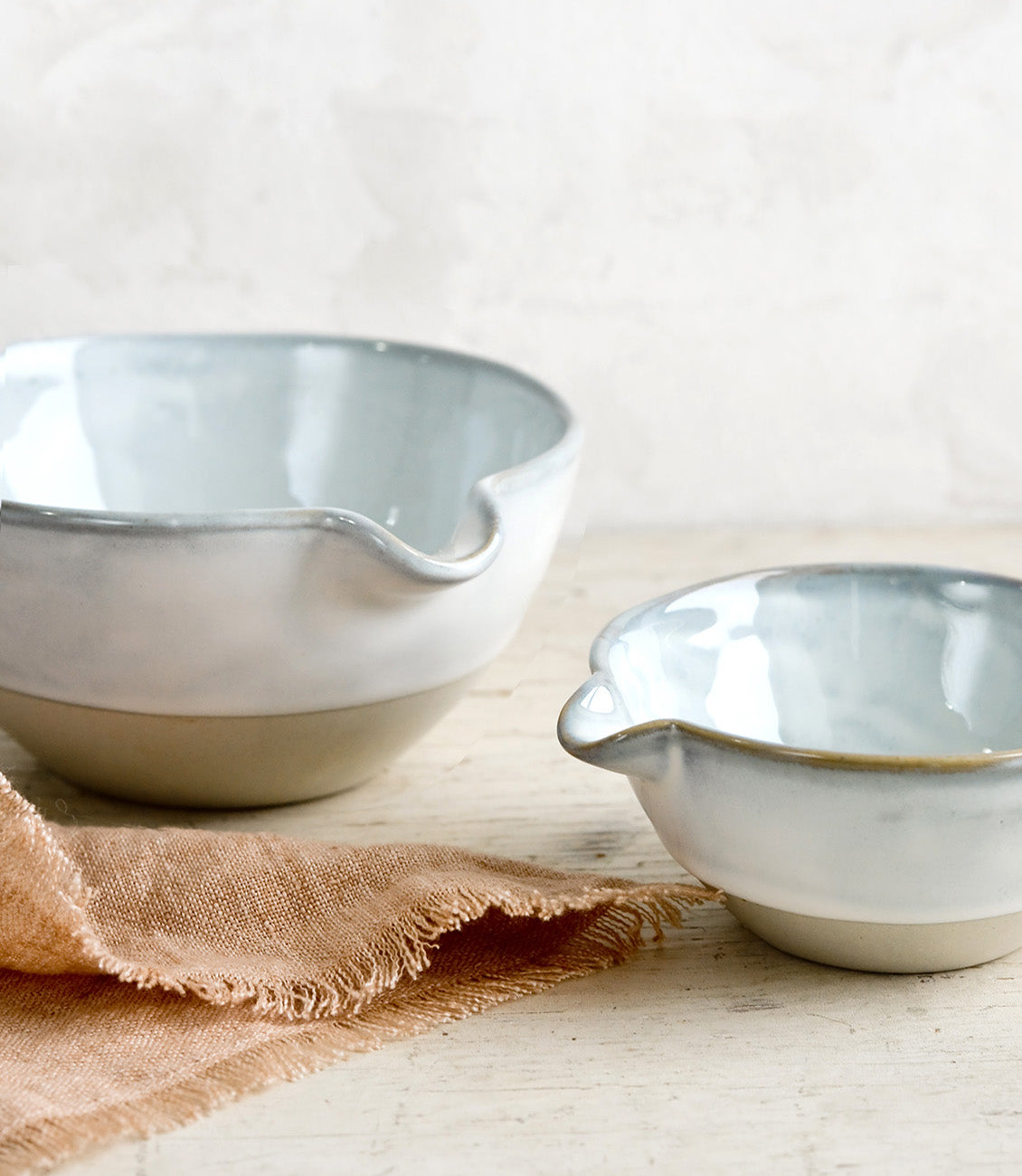 Two ceramic bowls with pouring spouts in large and small sizes.