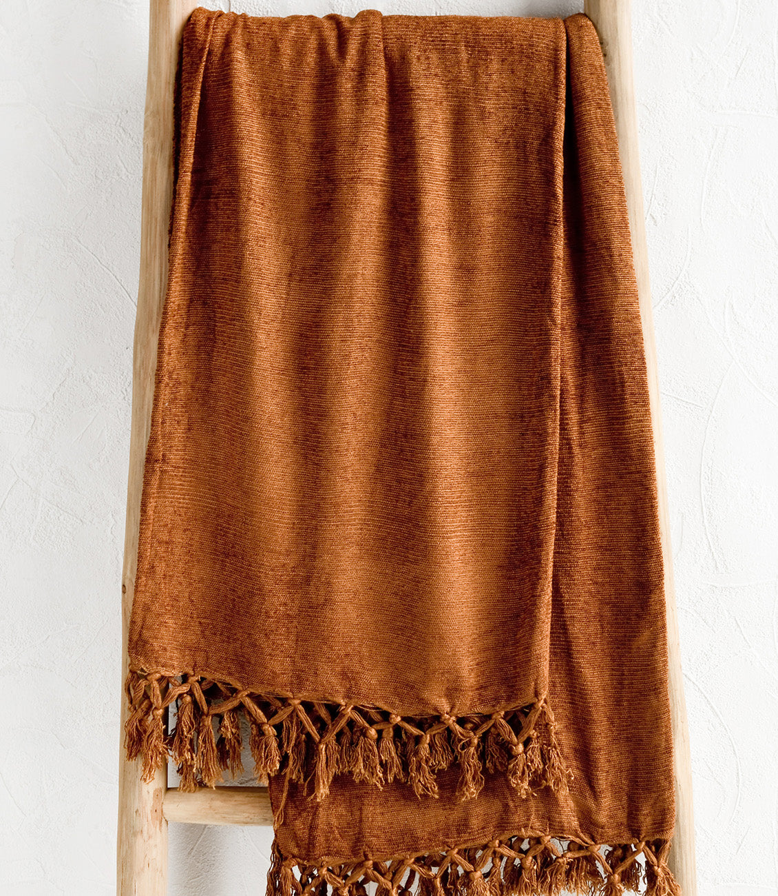 A chenille throw with knotted tassel trim in nutmeg copper color.