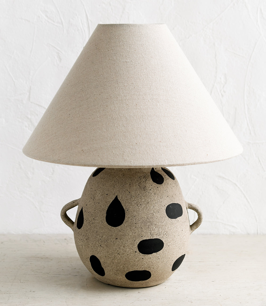 A table lamp with black woven base and linen shade.