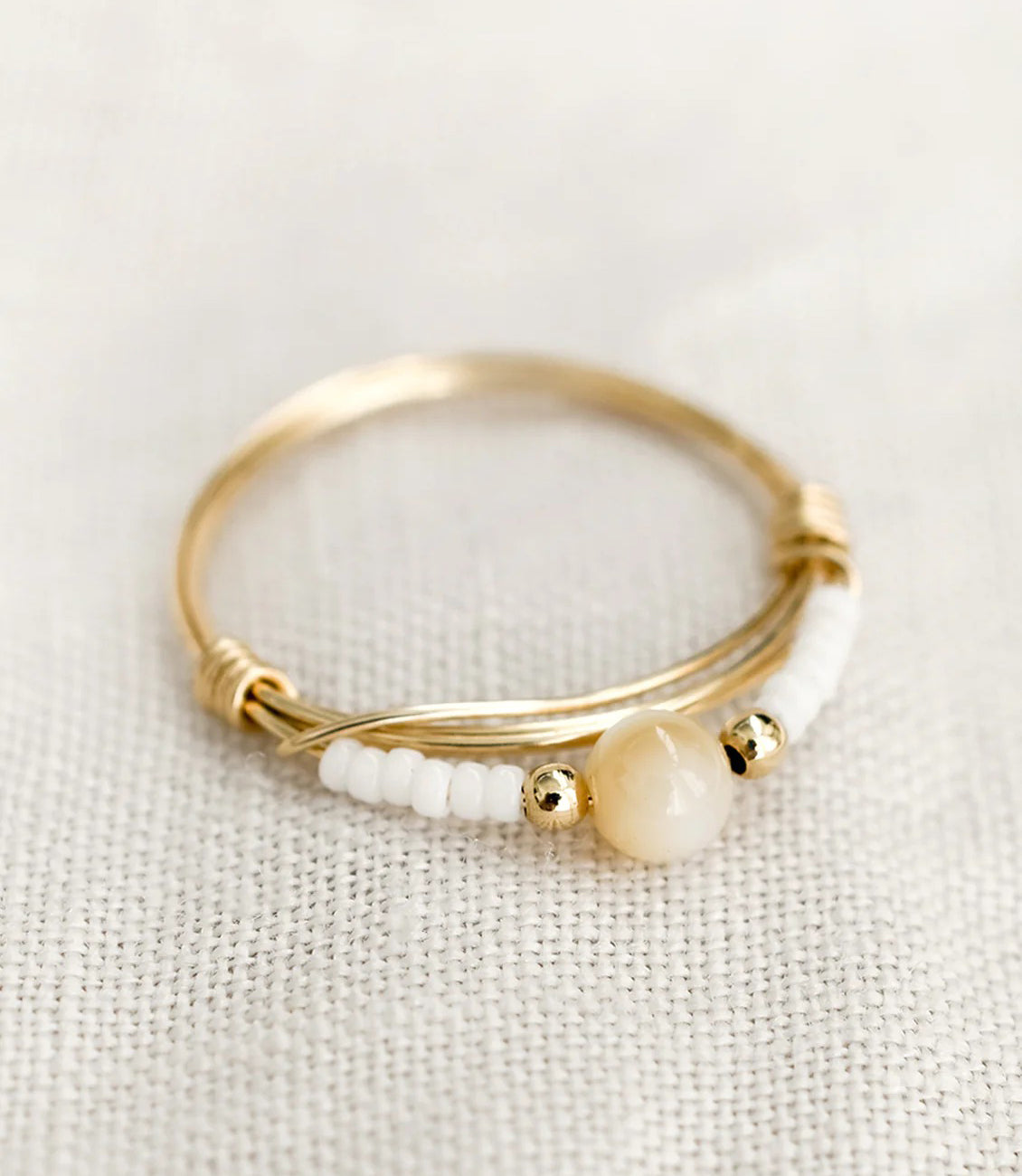 A gold round bezel ring showing white flower on clear background.