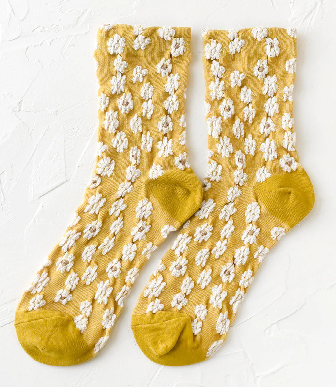 A pair of oatmeal colored socks with raised diamond texture and orange flowers.