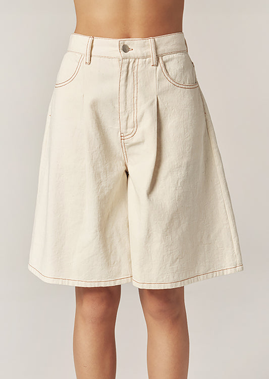 Beige denim shorts worn by a person on a plain background