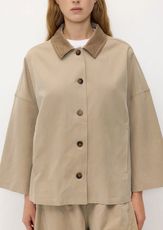 A person wearing a hip-length A-line jacket in khaki with tan contrast collar.