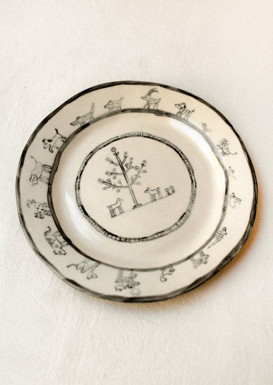 A cream ceramic plate with hand drawn animal print.