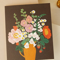 2: A greeting card with floral arrangement on brown background.