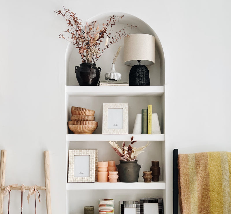 An archway of shelves decorated with an assortment of home goods