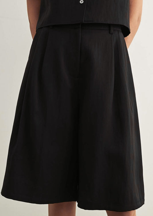 A person wearing a pair of tailored knee-length shorts in black.