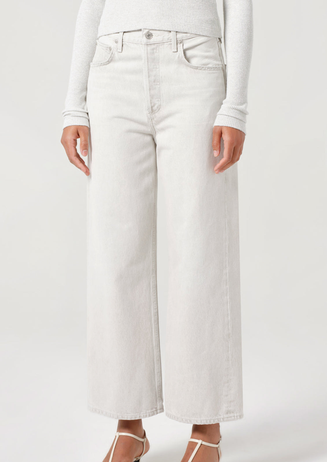 A person wearing a pair of wide leg jeans in light white-grey wash.